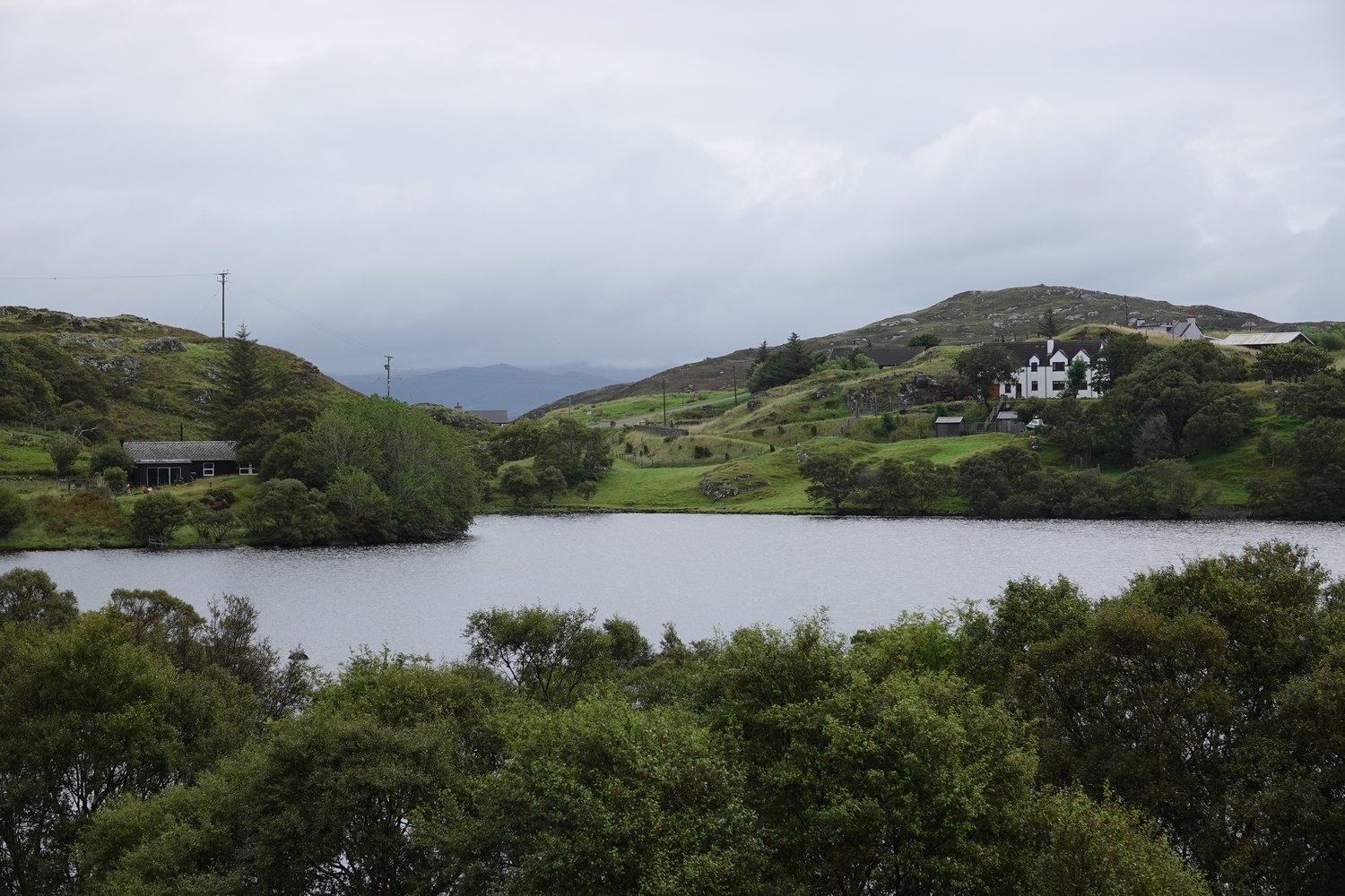 Loch Drumbeg surrounded by green hills and scattered houses